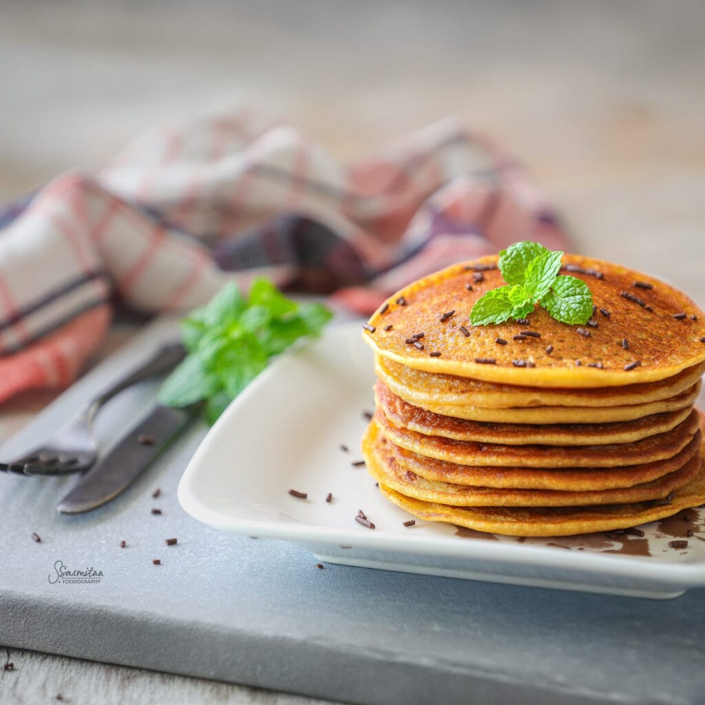 Stack of soft mango paneer pancakes topped with fresh mangoes