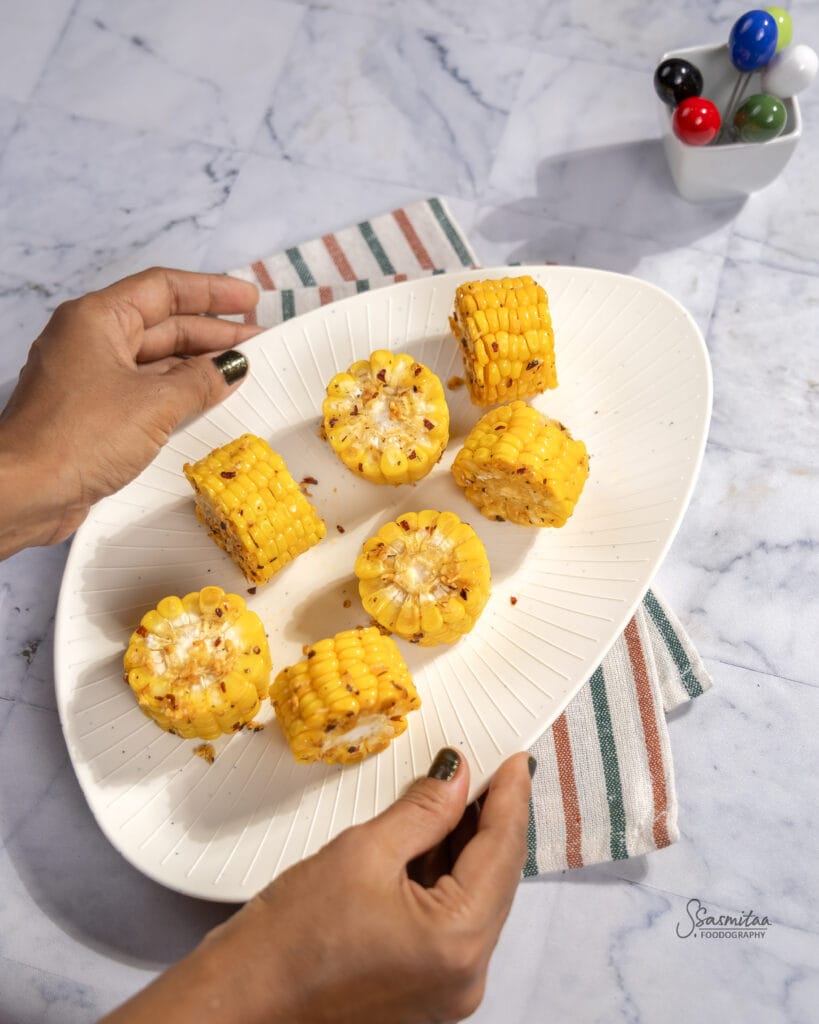 Close-up of buttery garlic sweet corn seasoned with herbs and chilli flakes