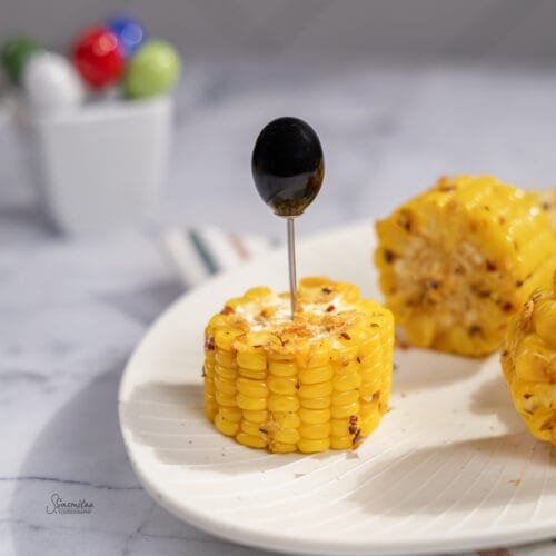 Spicy Butter Garlic Corn Recipe served on a white plate with butter, garlic, and chilli flakes