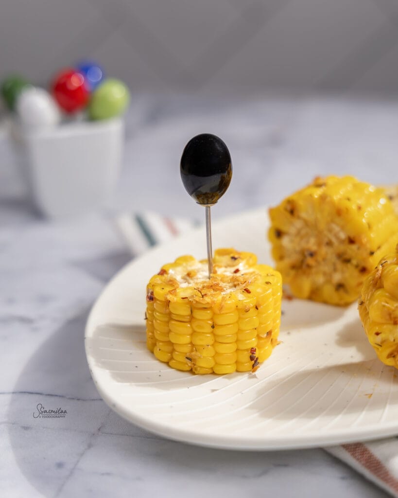 Spicy Butter Garlic Corn Recipe served on a white plate with butter, garlic, and chilli flakes